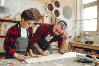 Cetvelli ve kalemli adamlar iş için tahta ölçüyorlar.