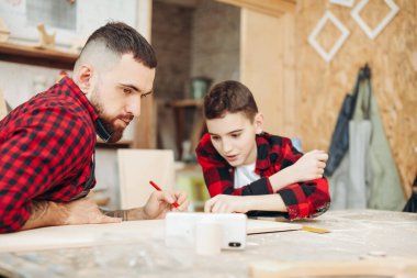 Baba ve oğul atölyede ahşap bir uçağın modelini tasarlıyorlar.