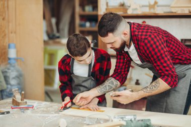 Baba ve oğul atölyede ahşap bir uçağın modelini tasarlıyorlar.