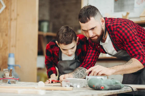 Pai e filho na oficina jogando projetar um modelo de um avião de madeira — Fotografia de Stock