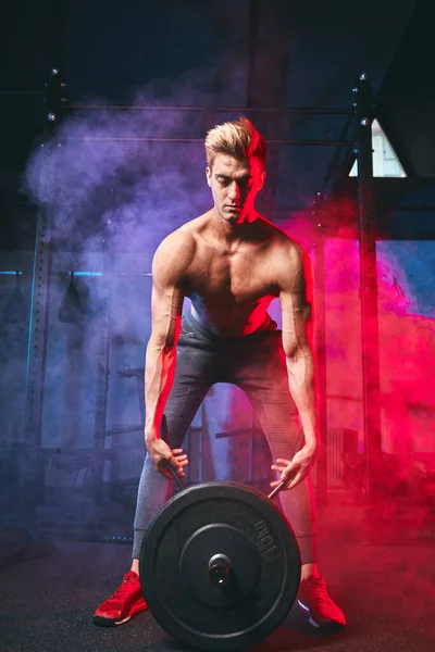 Kaukasiska fitness man lyfta tung platta av skivstång under träning i gym — Stockfoto