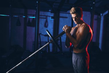 Kafkas kaslı vücut geliştirici spor salonunda demir parmaklıklar üzerinde ağırlık plakaları esnetiyor.