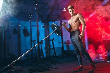 Kafkas kaslı vücut geliştirici spor salonunda demir parmaklıklar üzerinde ağırlık plakaları esnetiyor.