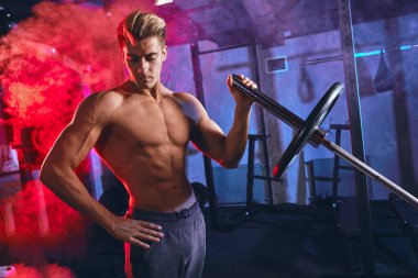 Spor salonunda ağırlık kaldırmadan önce erkek antrenör ağırlık plakasını haltere yüklüyor.