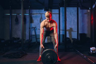 Kafkas kaslı vücut geliştirici spor salonunda demir parmaklıklar üzerinde ağırlık plakaları esnetiyor.