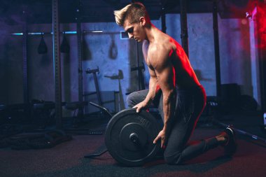 Kafkas fitness adamı spor salonunda ağır halter kaldırıyor.