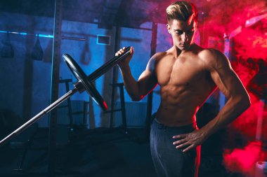 Yakışıklı beyaz vücutlu adam spor salonunda halterle çapraz egzersiz yapıyor.