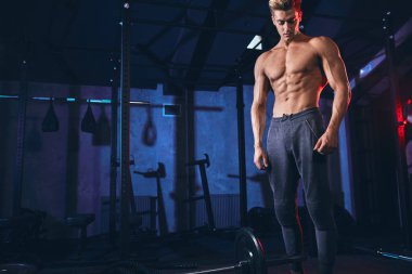 Spor salonunda ağırlık kaldırmadan önce erkek antrenör ağırlık plakasını haltere yüklüyor.