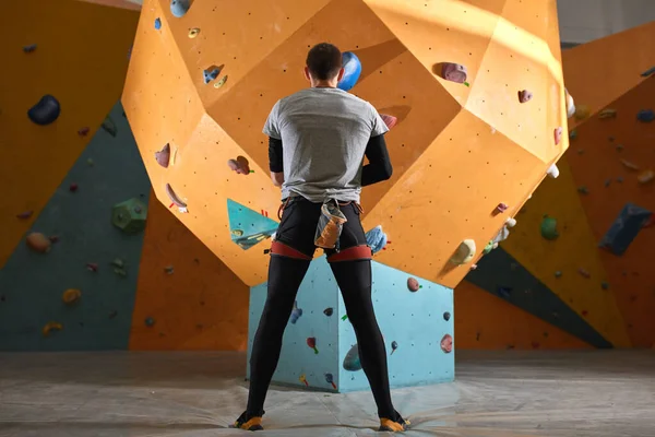 Rockero con problemas físicos de pie frente a la pared de escalada artificial — Foto de Stock