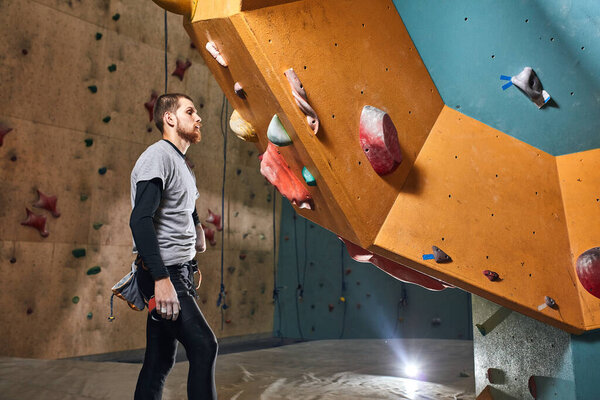 Athletic sportsman without forearm standing in front of artificial rock wall