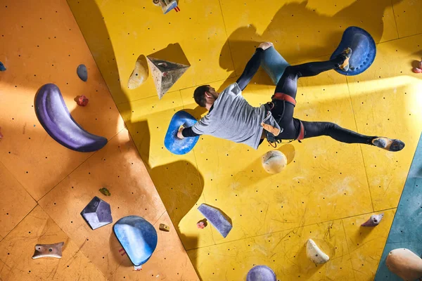Sarı tırmanma duvarında yapay taşlarla ön kol eğitimi almadan tırmanan biri. — Stok fotoğraf