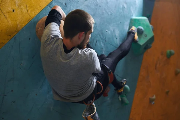 Esportista se movendo na parede de rocha artificial, preparando-se para a montanha extrema ascender — Fotografia de Stock