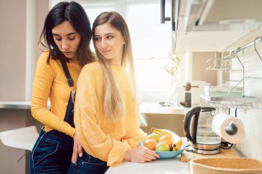 Kızlar yan yana durur ve mutfakta flört ederler.,
