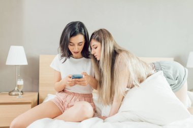 Açık ve koyu renk saçlı kadınlar mesaj okuyor, internette geziniyorlar.