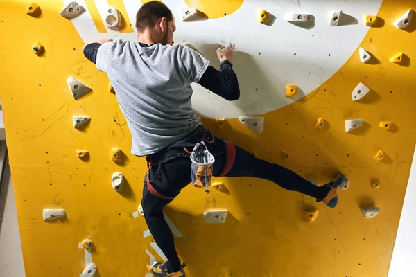 Escalador con problemas físicos entrenando duro, subiendo a la pared de roca amarilla —  Fotos de Stock