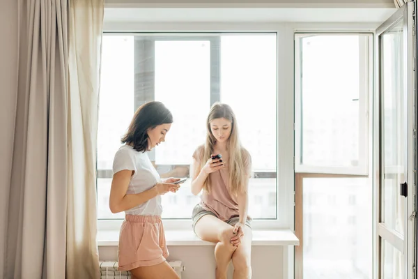 Две красивые девушки используют свои смартфоны — стоковое фото