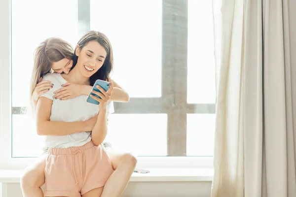 Garotas positivas alegres ter grande momento, brincando ao usar um gadget . — Fotografia de Stock