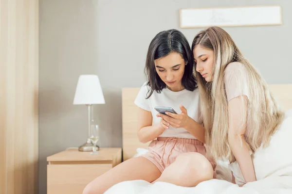 Twee jonge mooie vriendinnen zitten in de slaapkamer — Stockfoto