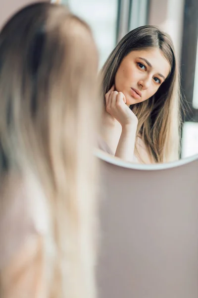 Menina incrível com cabelo longo e claro olhando no espelho em casa — Fotografia de Stock