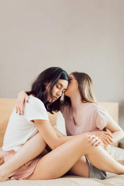 Blond meisje zoenen een donkerharige vrouw op haar voorhoofd — Stockfoto