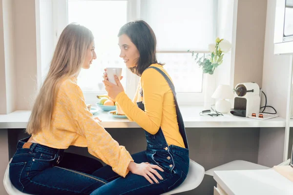 Duas meninas bonitas tomando uma bebida em casa pela manhã — Fotografia de Stock