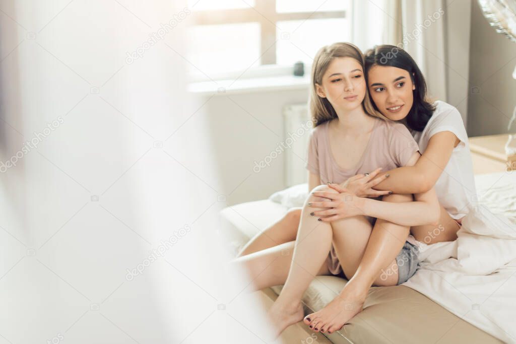 two beautiful lesbians in casual clothes sitting in the bedroom
