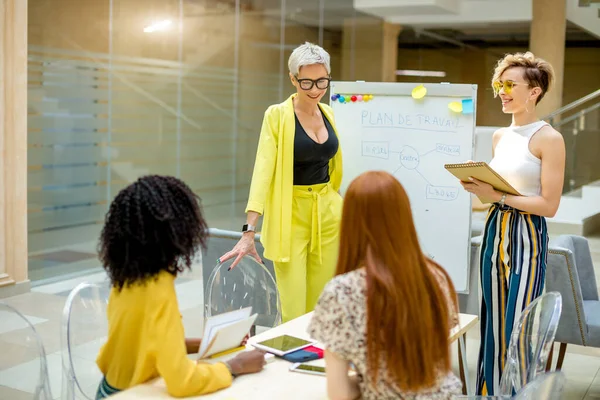 Elegante capo femminile e il suo assistente stanno presentando grafico sulla lavagna — Foto Stock