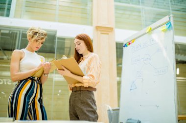 Elinde evrakları olan iki ciddi kız işe odaklanmış..