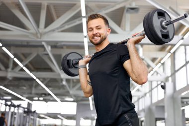 Yakışıklı atletik adam halterlerle kaslarını şişiriyor.