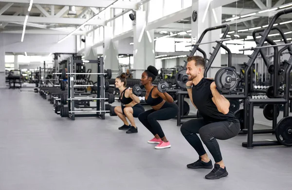 Entraîneur caucasien enseigne des exercices avec des poids aux femmes attrayantes — Photo