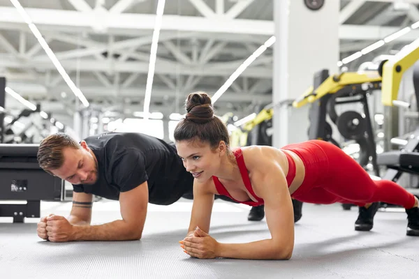 Jeune homme et femme debout en position de planche au gymnase — Photo