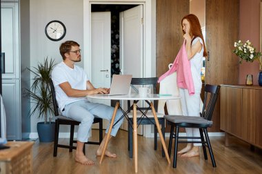 Kızıl saçlı kadın kocasının kıyafetini sevip sevmediği sorusuyla ilgileniyor.