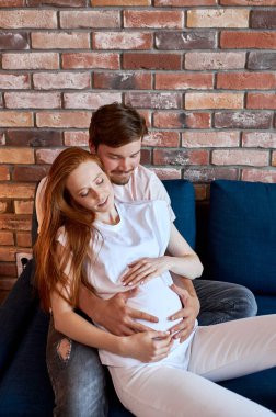 Dikkatli bir adam hamile bir kadının karnını okşar.