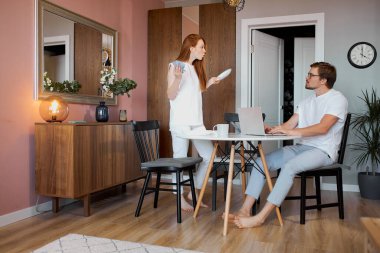 Kızıl saçlı kadın evde çalışan bir adamla kavga ediyor.