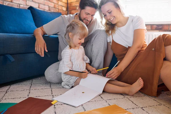 Uvolněné šťastní rodiče sedět s dcerou na podlaze — Stock fotografie
