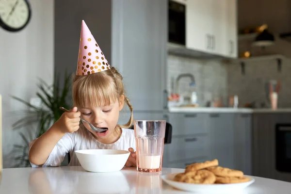 Petit enfant fille assis avoir le petit déjeuner portant chapeau de fête — Photo