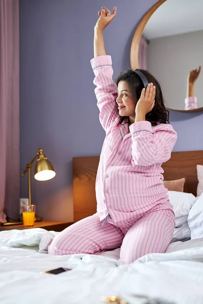 Красивая беременная женщина слушает музыку в постели — стоковое фото