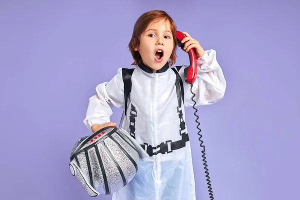 Sorprendido niño pequeño en traje de astronauta hablando por teléfono — Foto de Stock