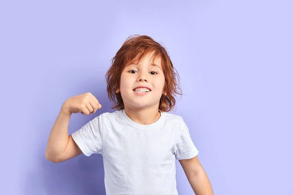 Stark liten pojke i vit T-shirt som visar musklerna — Stockfoto