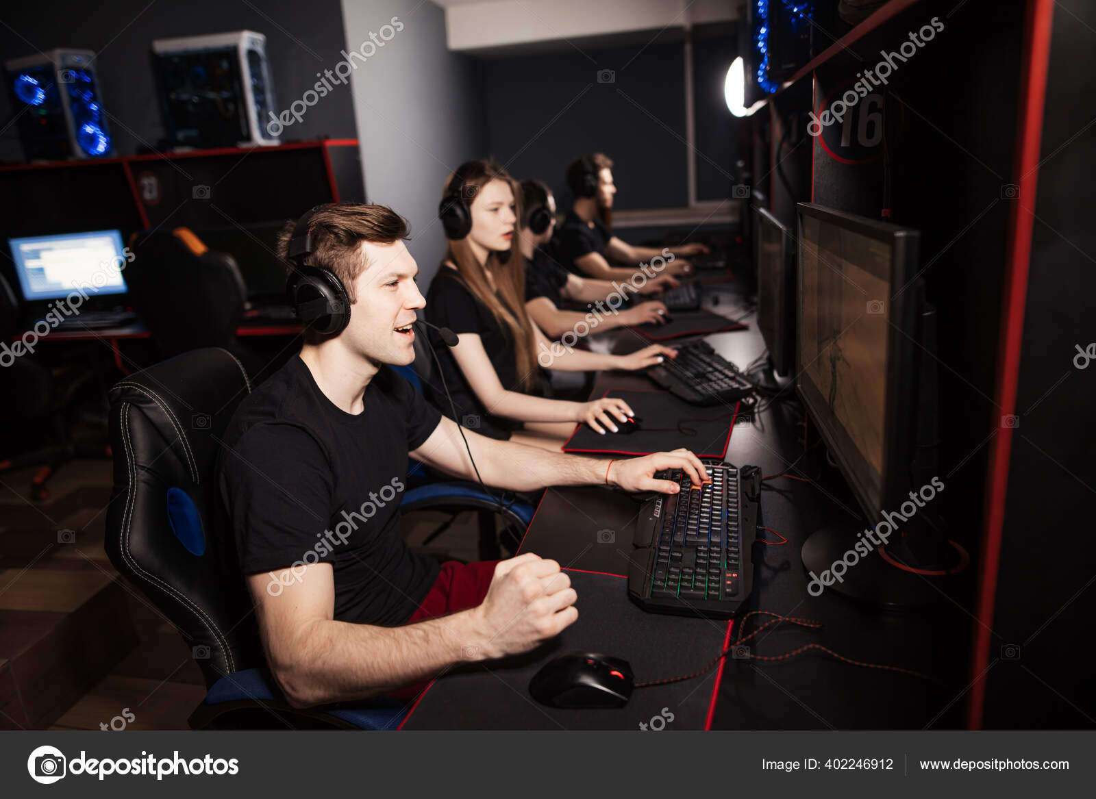 Grupo de jogadores adultos sentam-se em fila atrás dos monitores