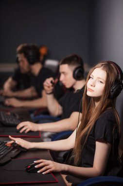 Genç kız, klüpte online video oyununda yanında oturan insanlarla oynuyor.