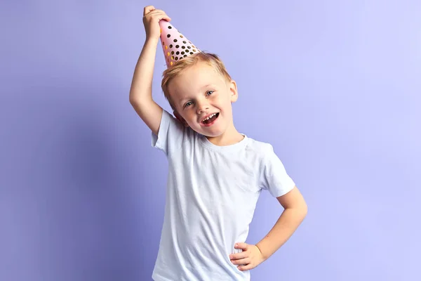 Divertido chico caucásico en gorra de cumpleaños aislado sobre fondo púrpura —  Fotos de Stock