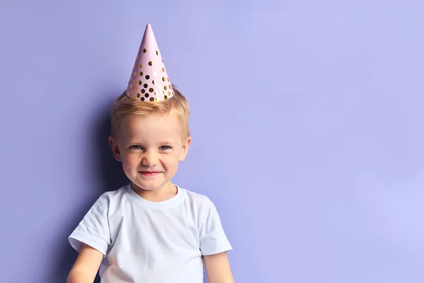 Garoto caucasiano engraçado em boné de aniversário isolado em fundo roxo — Fotografia de Stock