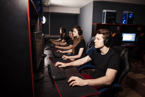 Gruppe erwachsener Spieler sitzt in Reihe hinter den Monitoren und spielt in PC-Spielecenter. — Stockfoto