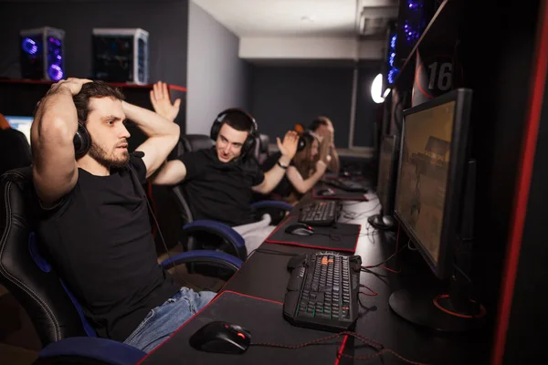 Emotional scene in pc gaming club where one gamer succeed, another lost battle