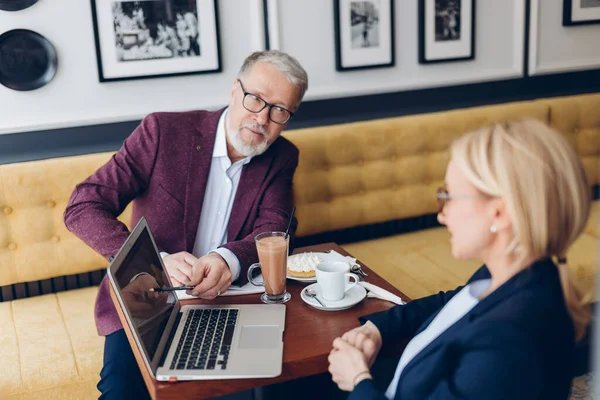 Viejo hombre guapo coqueteando con su colega mientras discute el plan de trabajo — Foto de Stock