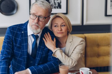 Düşünceli, harika bir çift kafede kahvaltı yapıyor ve yan bakıyor.