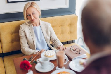 Güzel bayan kafede oturuyor ve arkadaşını dinliyor.