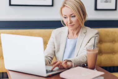 Kafede dinlenirken zarif bir kadın oyun oynuyor.