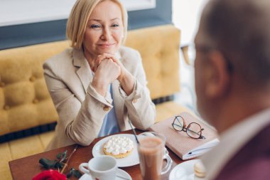 Sarışın kadın restoranda randevudan zevk alıyor masada oturmuş adama bakıyor.